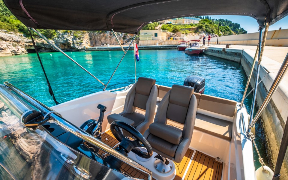 Shaded motorboat seating beside a turquoise harbor